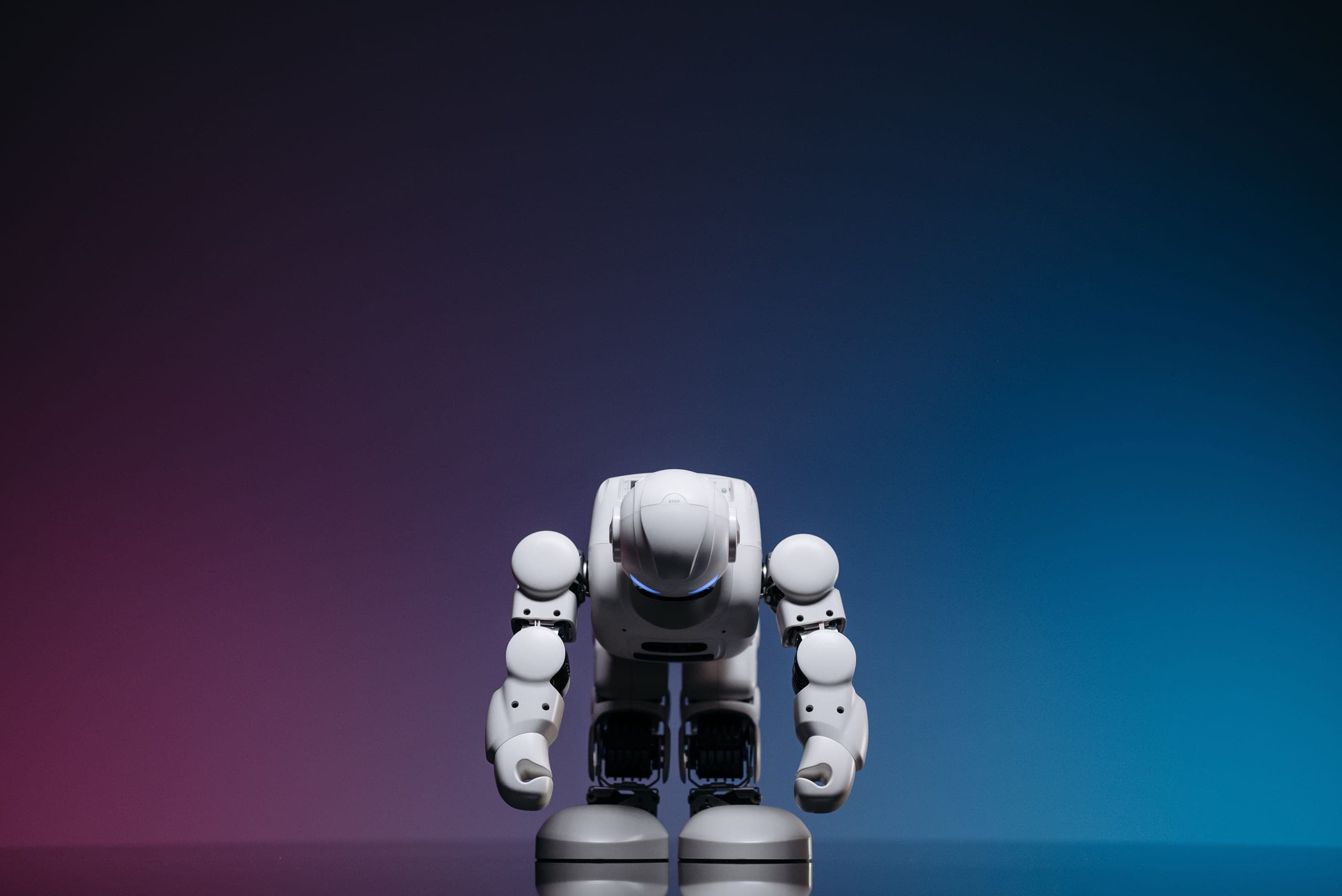 Close-up of a white toy robot against a blue and pink gradient background